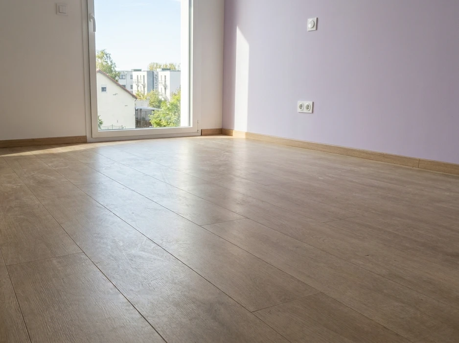 Pièce vide et lumineuse avec sol en parquet stratifié imitation chêne clair, pose en lames larges à joints décalés