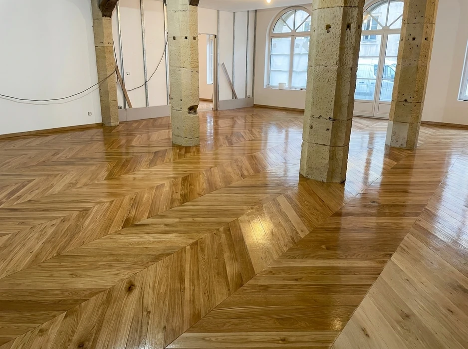 Parquet en point de Hongrie (chevrons) en chêne massif verni brillant, posé dans un espace en rénovation