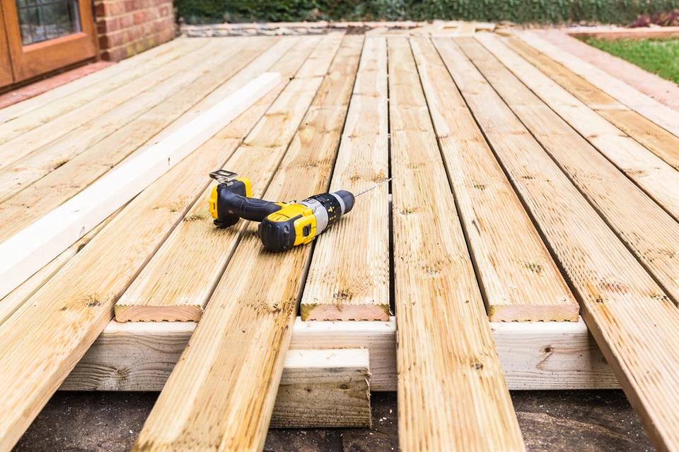 Terrasse extérieure en construction avec planches de bois naturel posées sur solives