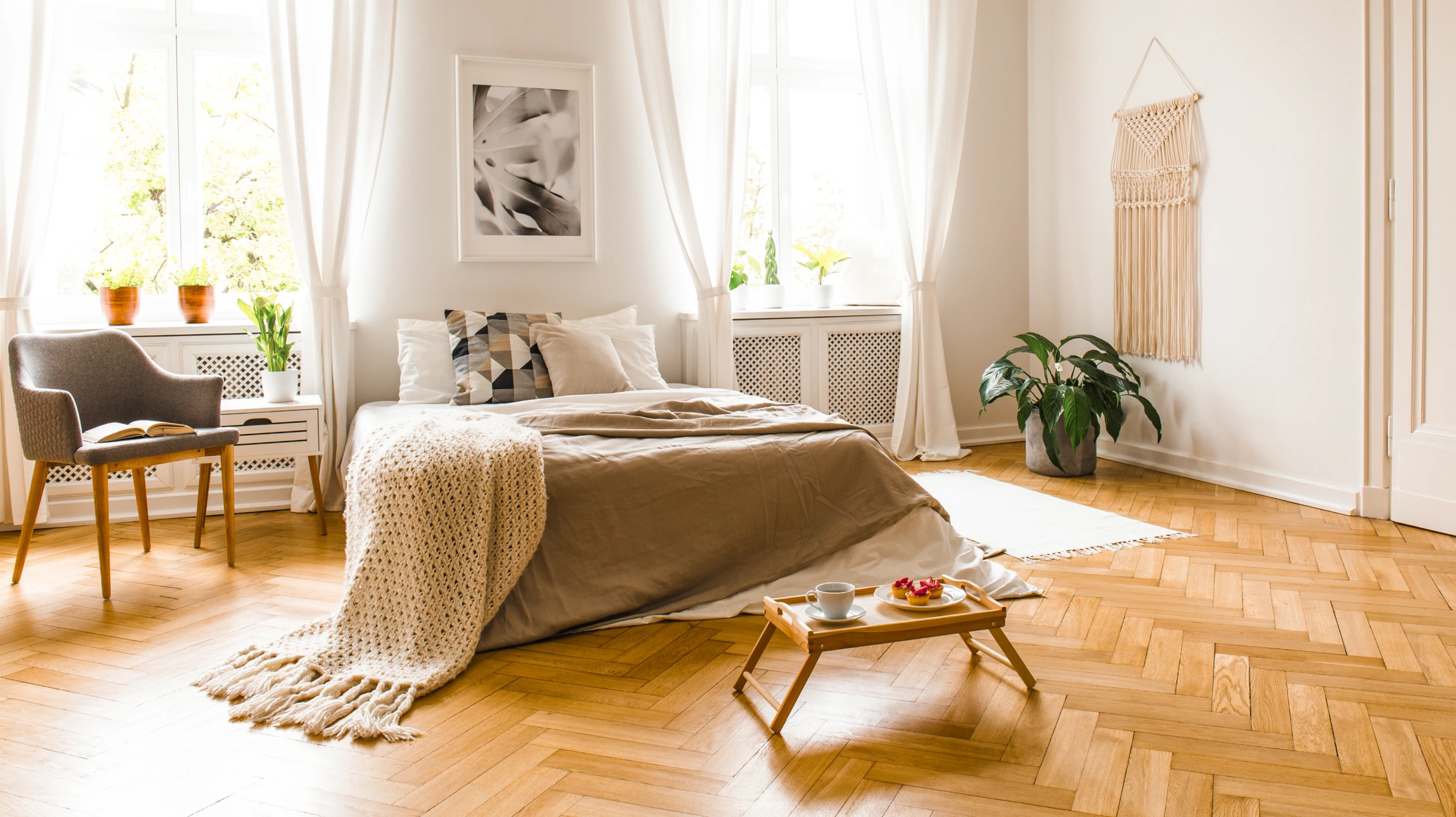 Artisan à genoux installant du parquet dans une pièce blanche, mesurant une lame avec un mètre ruban